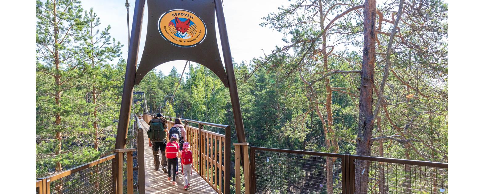Lapsiperhe ylittää Lapinsalmen siltaa Repoveden kansallispuistossa